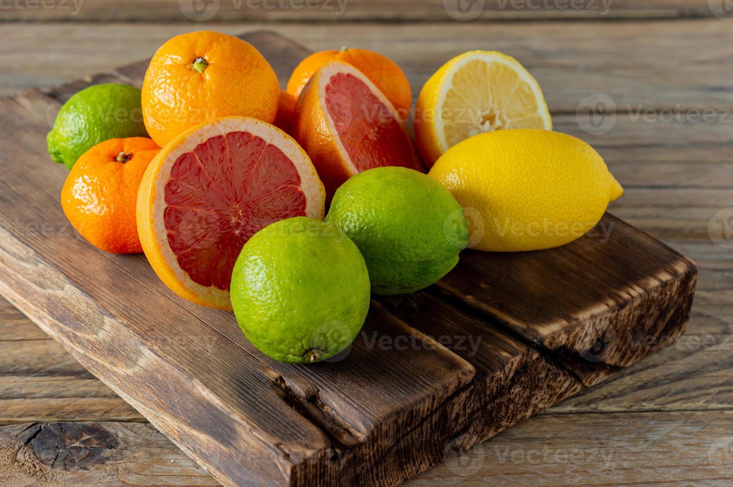 helften van vers citrus fruit Aan houten achtergrond. oranje, pompelmoes, limoen, citroen, mandarijn besnoeiing ringen foto