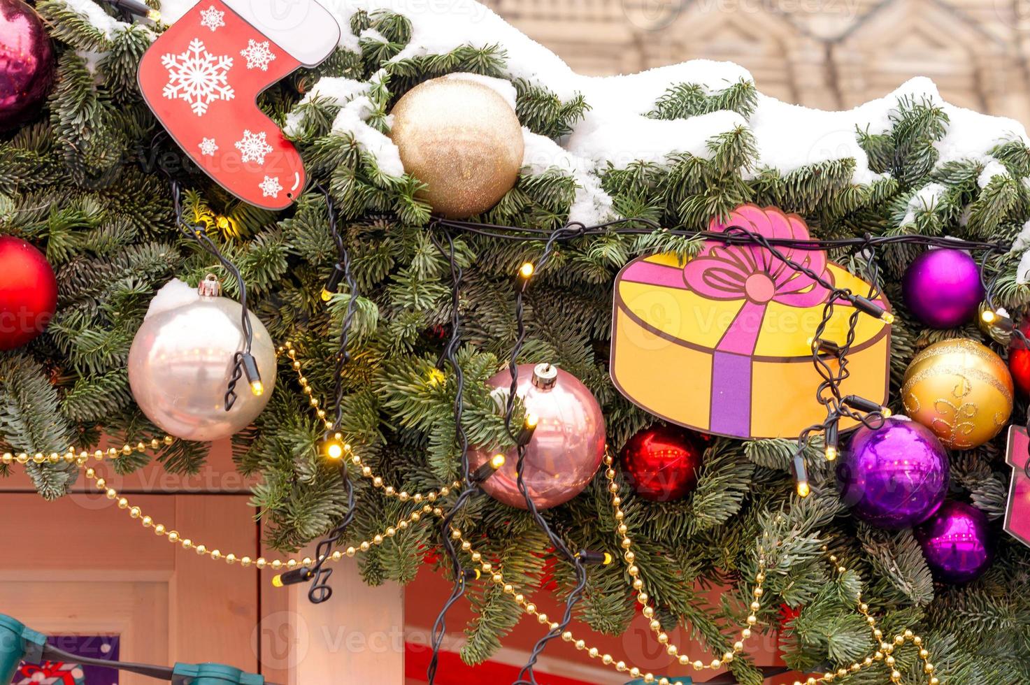 dichtbij omhoog van feestelijk Kerstmis stad decoratie. furie boom brunch gedekt met sneeuw versierd met kerstballen en slingers foto