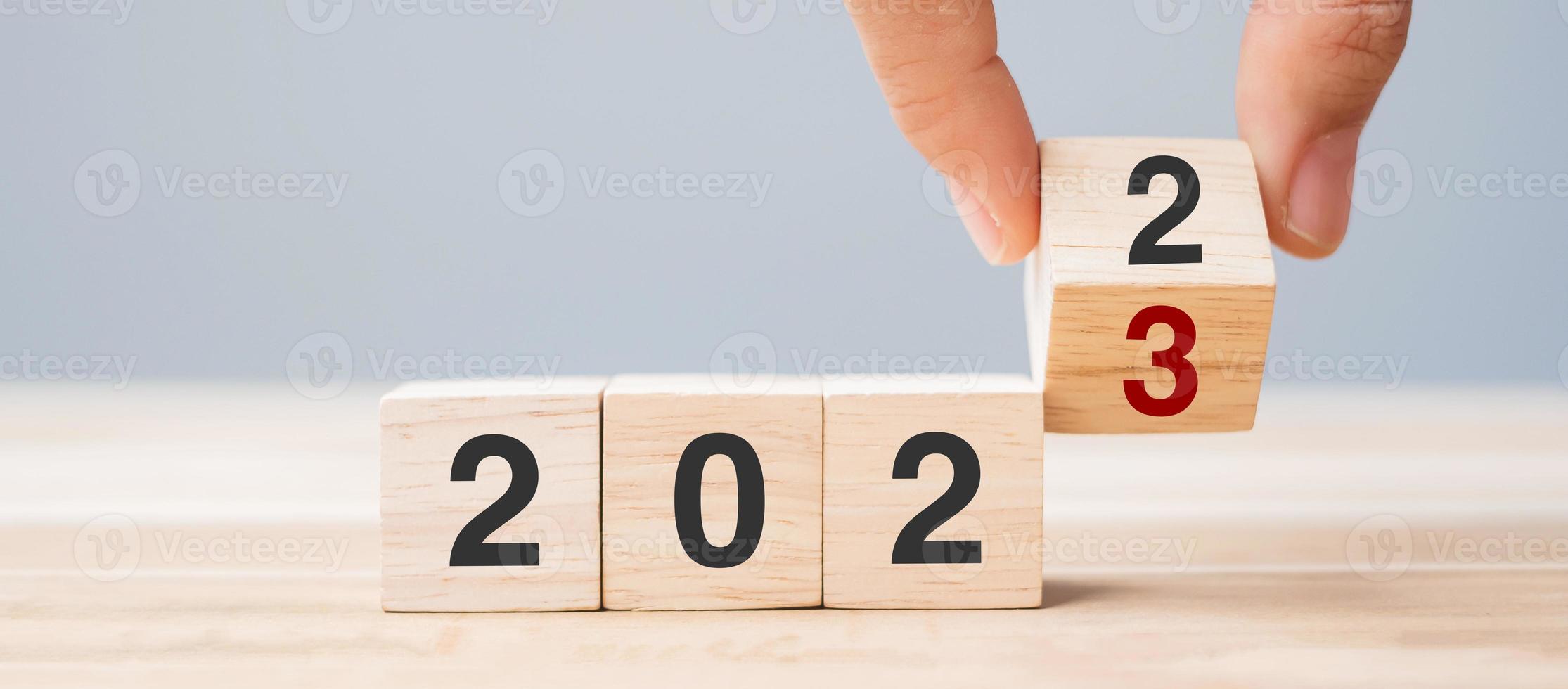 hand- omdraaien kubus blok 2022 naar 2023 tekst Aan tafel. oplossing, opnieuw bekijken, strategie, einde jaar, doel, bedrijf en nieuw jaar vakantie concepten foto