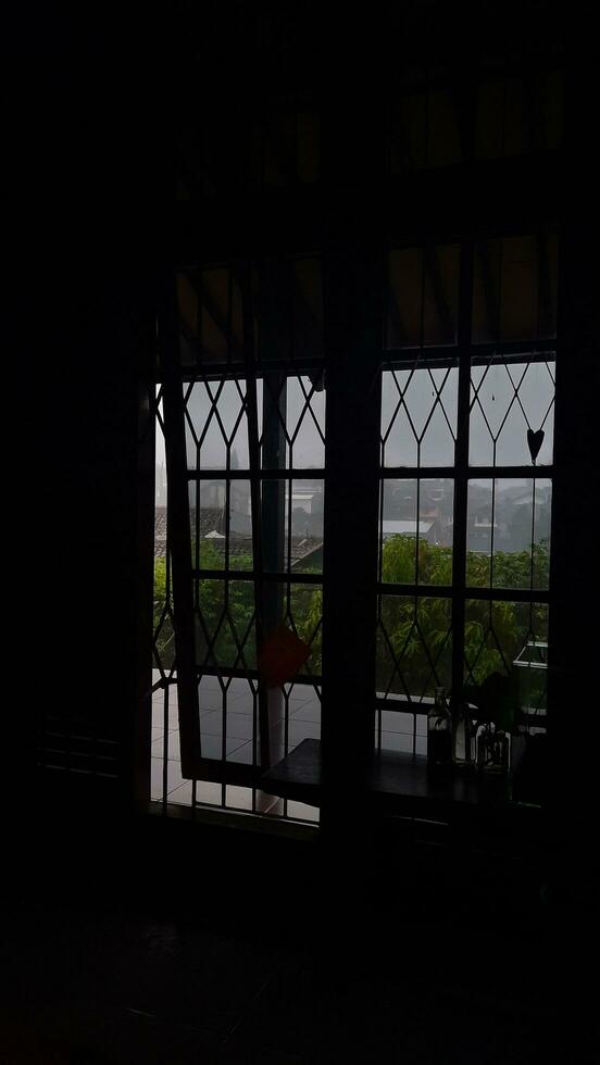 de schaduw van de venster van binnen de donker kamer met licht van buiten welke is ook bewolkt en regenachtig foto