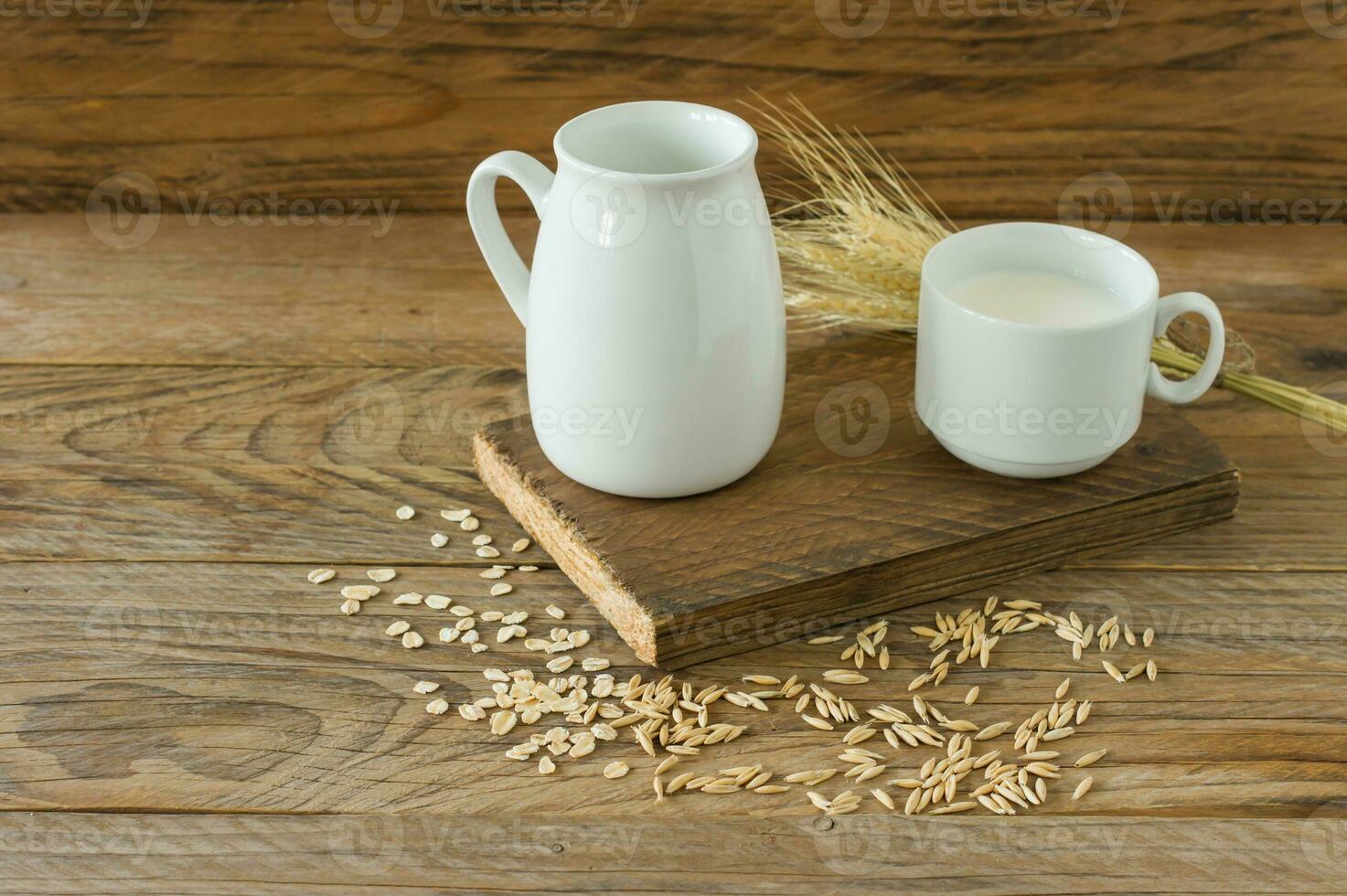 haver melk in glas werper en havermout in een kop Aan een houten tafel. foto