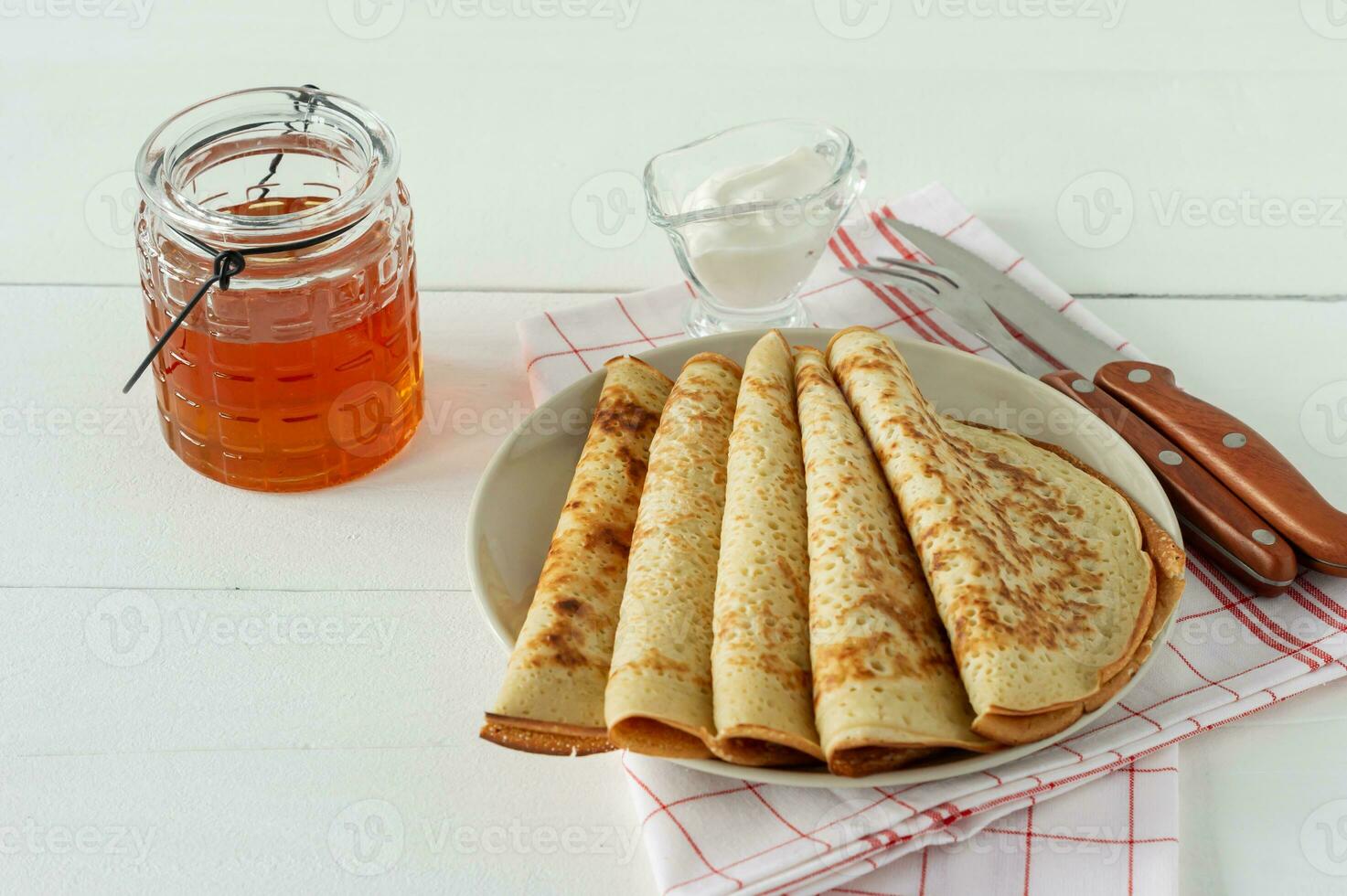 pannekoeken met honing siroop Aan een wit bord. traditioneel pannenkoeken voor pannenkoek week of vastenavond. foto