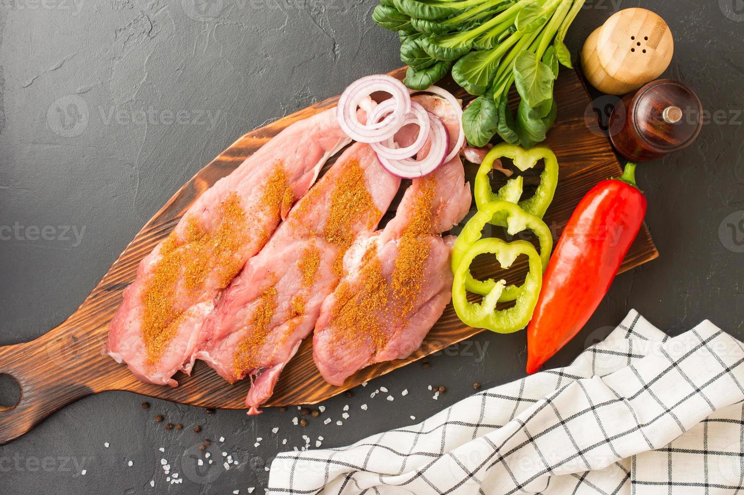 kant en klaar varkensvlees karbonades van boerderij vlees Aan een houten snijdend bord met specerijen voor bakken. zwart achtergrond. top visie. foto