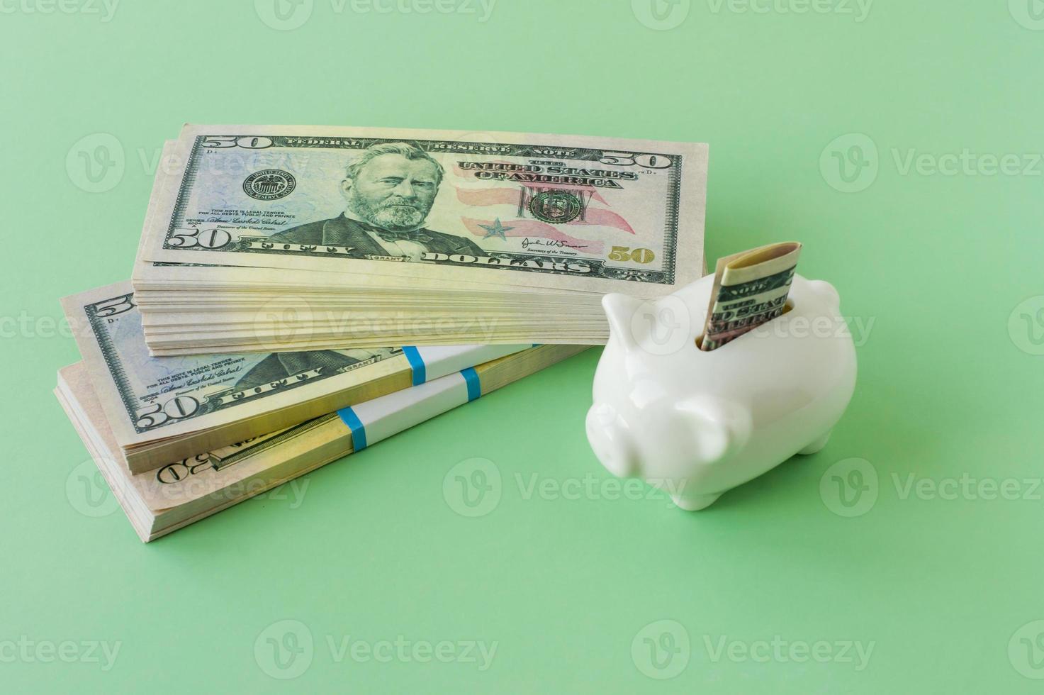 drie bank pakketten van 50 dollars geld Aan een groen achtergrond met een varkentje bank. de concept van financiën en accumulatie. foto