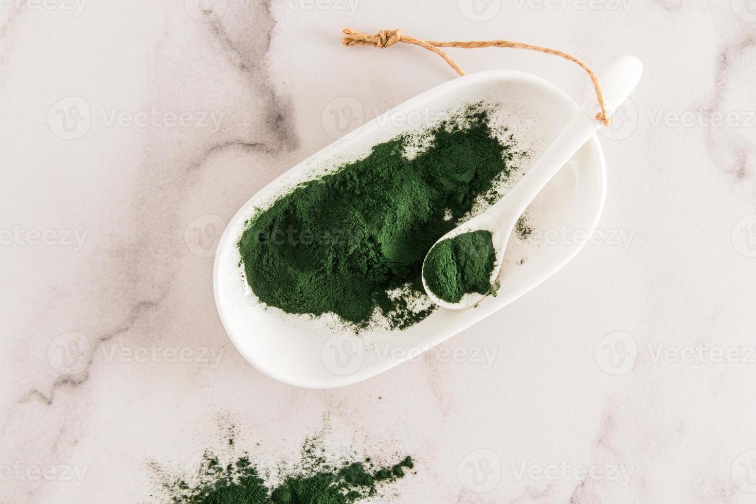 top visie van een kom van groen spirulina poeder Aan een marmeren wit achtergrond. alternatief naar geneesmiddel. onderhoud van immuniteit. foto