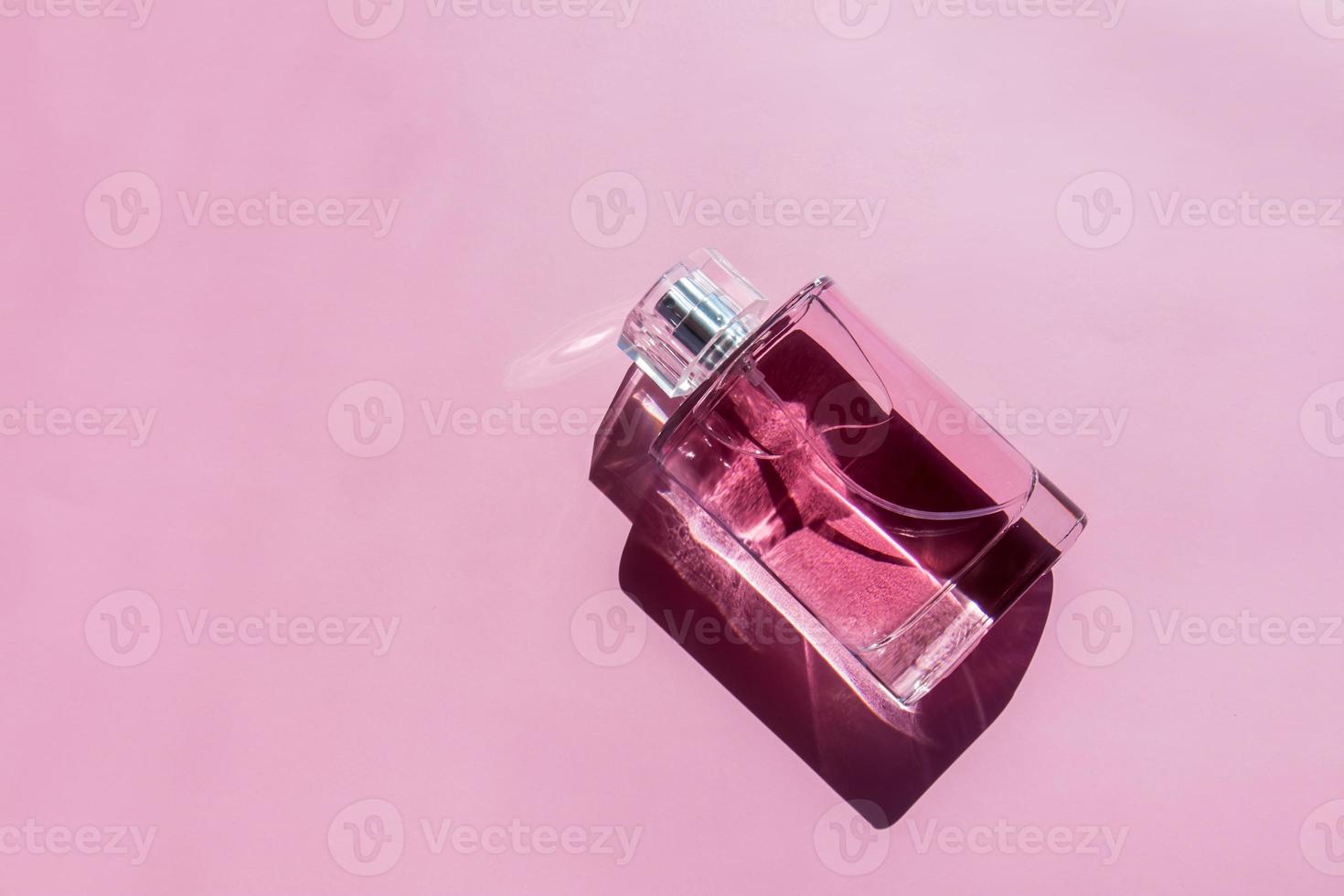 een fles van parfum of toilet water gemaakt van roze glas Aan een Purper achtergrond met mooi schaduwen. top visie. een kopiëren van de ruimte. foto