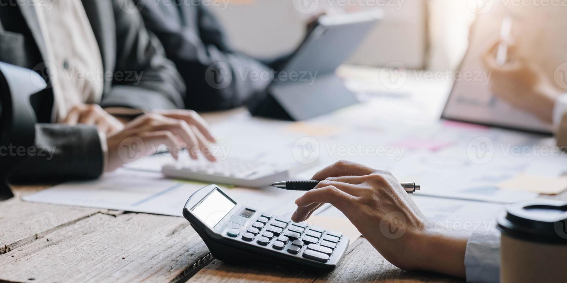 accountant of boekhouder die met rekenmachine werkt om samenvattend rapport met bedrijfsgegevens, boekhouddocument en laptopcomputer op kantoor te berekenen, concept voor zakelijke bijeenkomsten foto