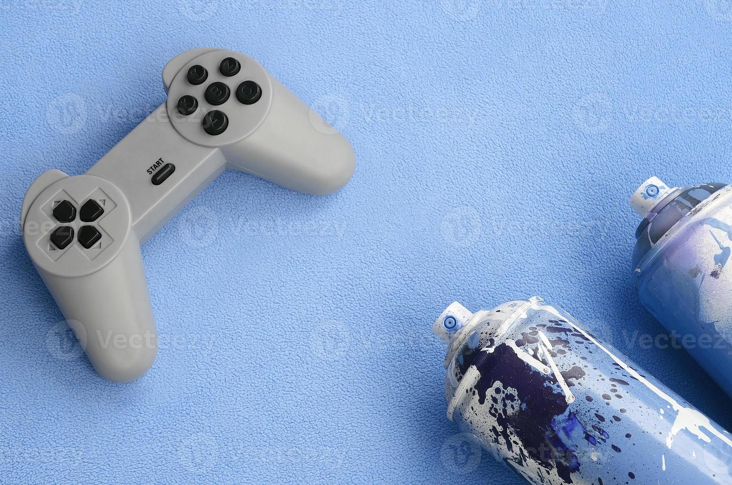 tieners en jeugd levensstijl concept. bedieningshendel en twee verstuiven blikjes leugens Aan de deken van harig blauw fleece kleding stof. controllers voor video spellen en verf blikjes Aan een pluche fleece materiaal achtergrond foto