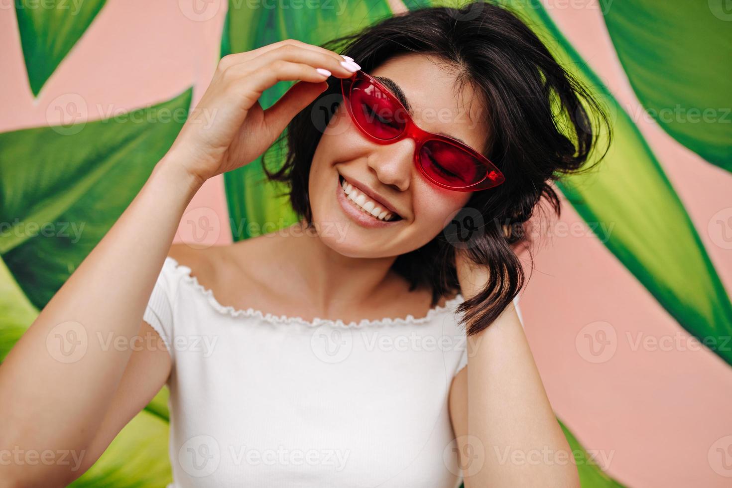 vrolijk jong vrouw glimlachen in voorkant van groen graffitti. elegant Kaukasisch meisje poseren in roze zo foto