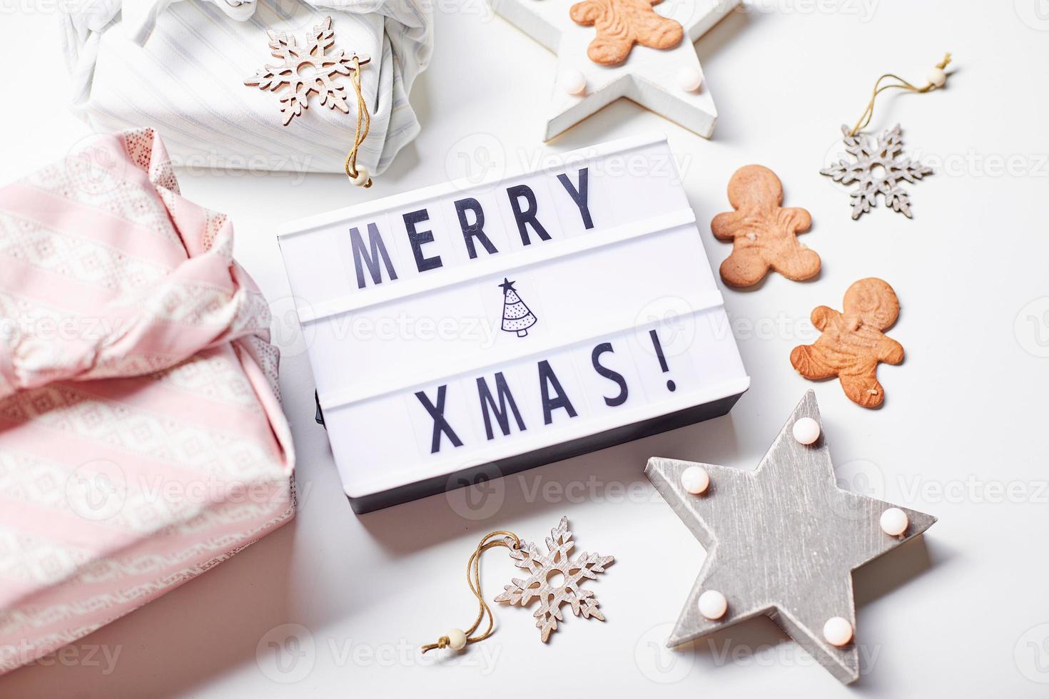 licht doos opschrift vrolijk kerstmis, cadeaus in Japans furoshiki stijl en peperkoek koekjes foto
