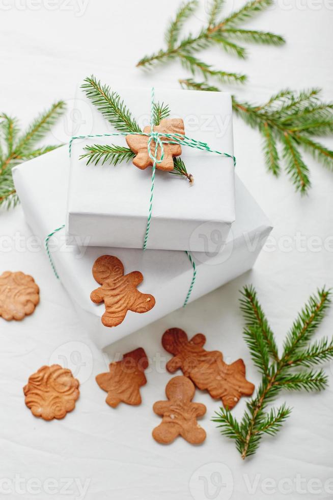 Kerstmis cadeaus verpakt in wit papier en versierd met net takjes en peperkoek koekjes foto