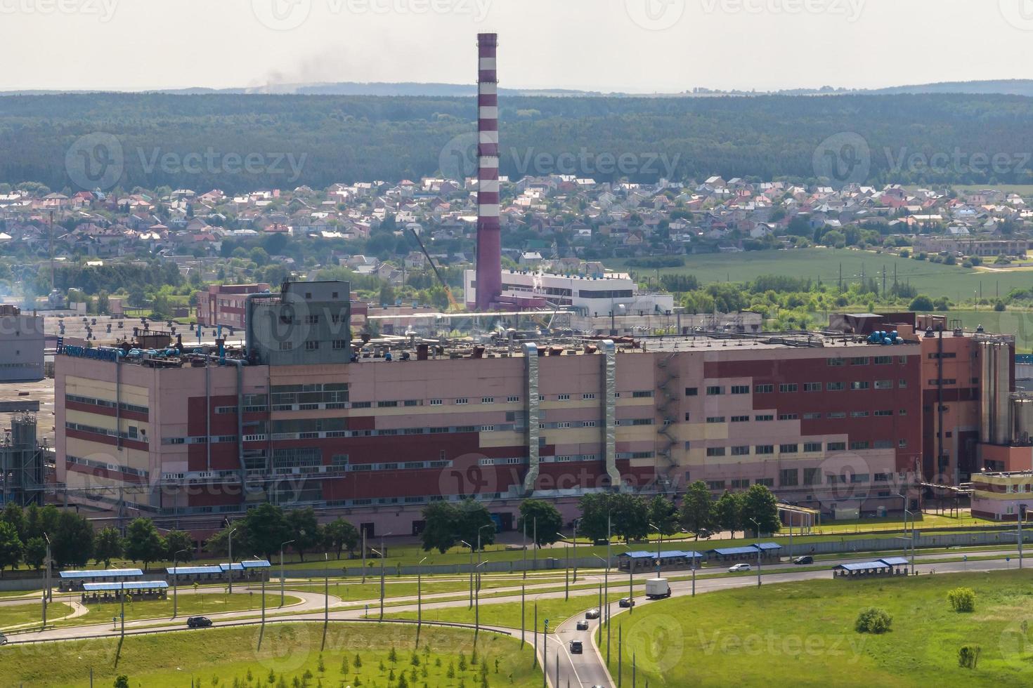 ariel panoramisch uitzicht over stad en wolkenkrabbers met een enorme fabriek met rokende schoorstenen op de achtergrond foto