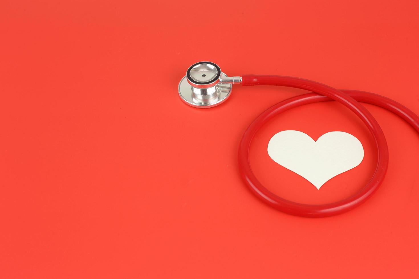wereld Gezondheid dag - cardiologie concept. controleren hart Gezondheid beschermen ziekte - stethoscoop met hart Aan rood achtergrond met copysapce foto