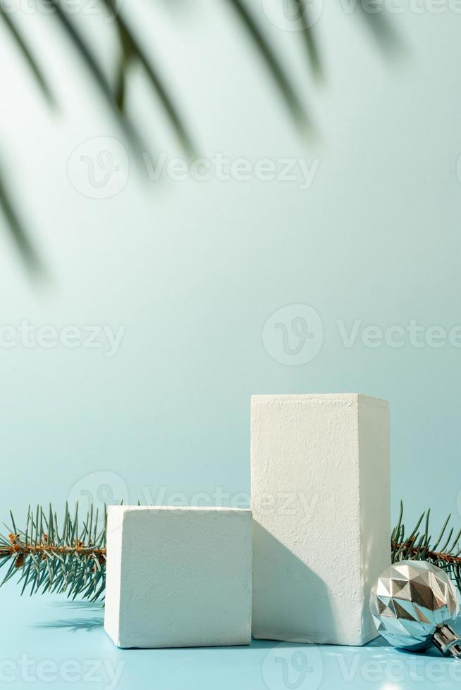 een minimalistisch tafereel van podia met Kerstmis decoratief ballen en pijnboom boom Aan licht blauw achtergrond foto