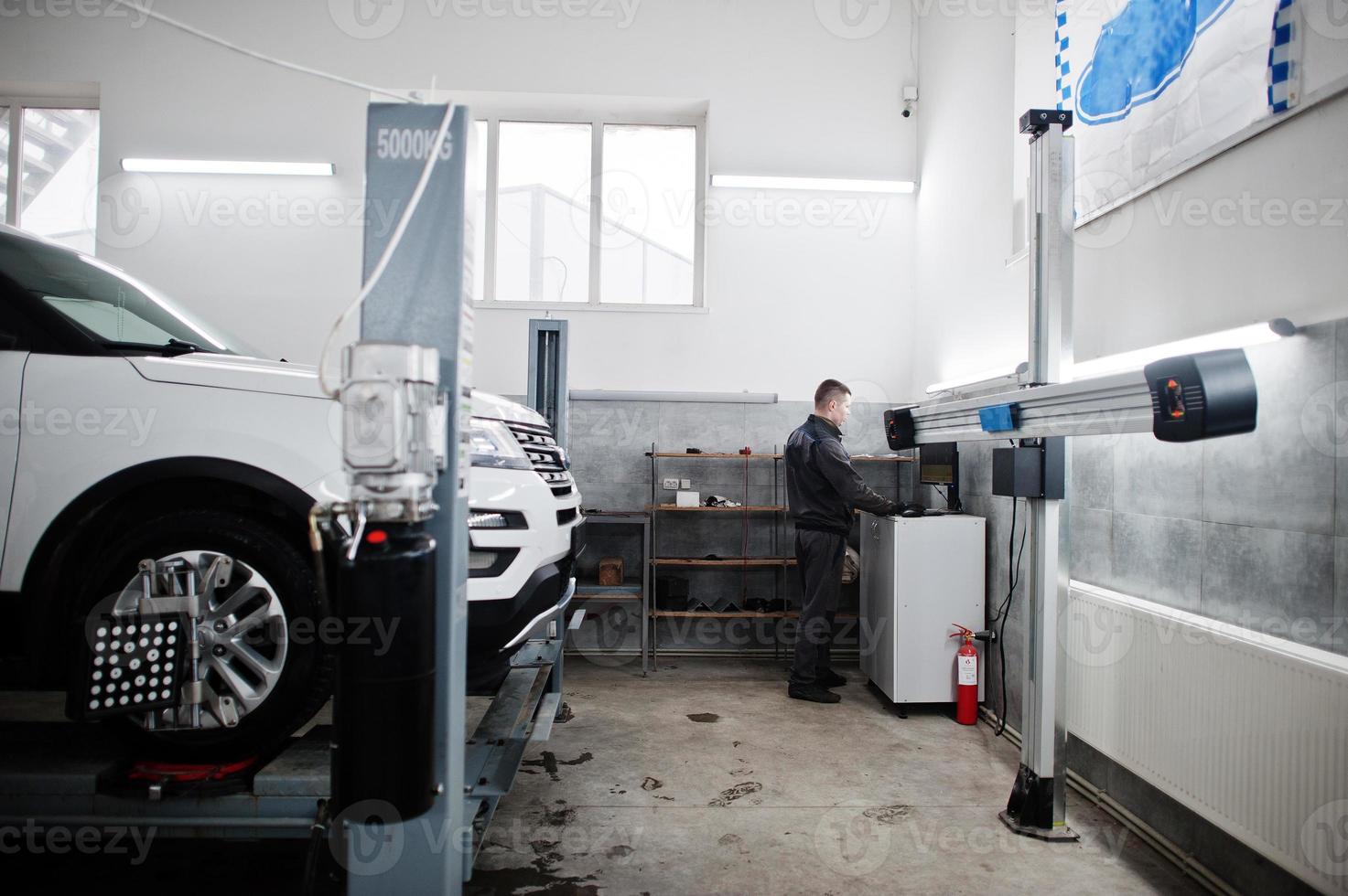 automonteur stelt Amerikaanse SUV-auto in voor diagnostiek en configuratie camber check in werkplaats van tankstation.. foto