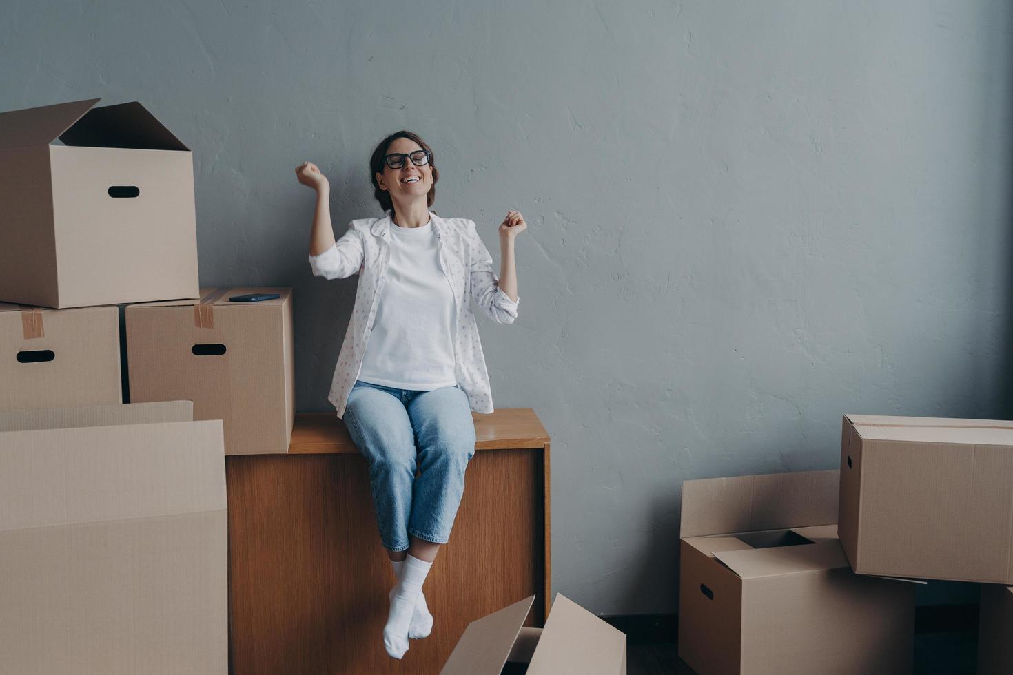 opgewonden vrouw aan het doen Ja gebaar viert verhuizing naar nieuw huis. in beweging dag, echt landgoed aankoop foto