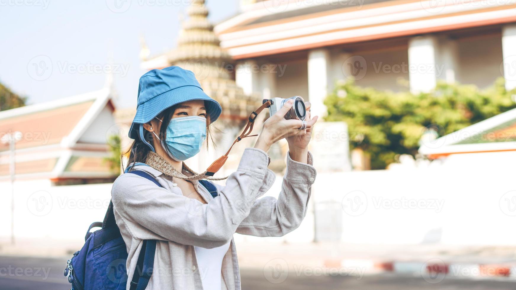 jonge volwassen aziatische vrouw rugzakreiziger draag gezichtsmasker neem een foto met de camera.
