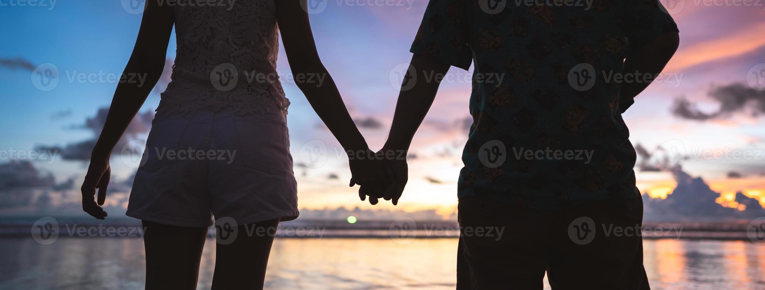 achterzijde visie van volwassen toerist Aziatisch liefde paar Holding hand- Aan de strand met zonsondergang lucht achtergrond foto
