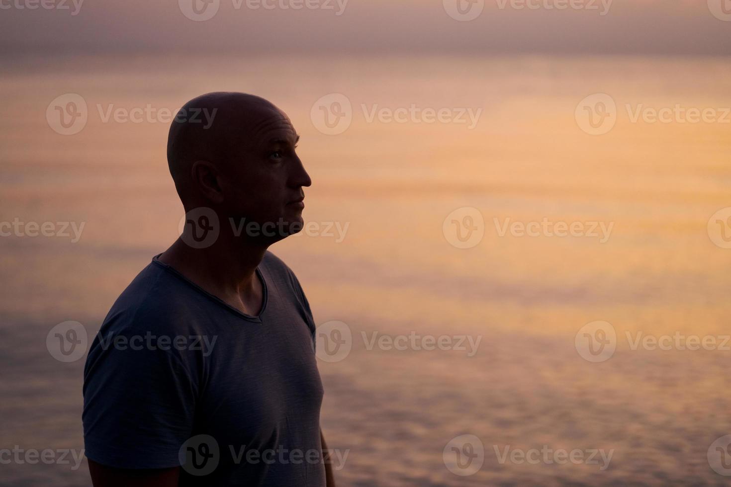 mannetje silhouet Aan achtergrond zee Bij zonsondergang looks naar kant alleen. Mens genieten van foto