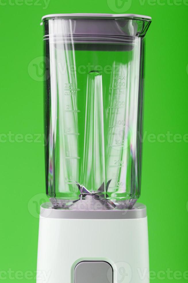 een wit blender met een leeg glas Aan een groen achtergrond. foto