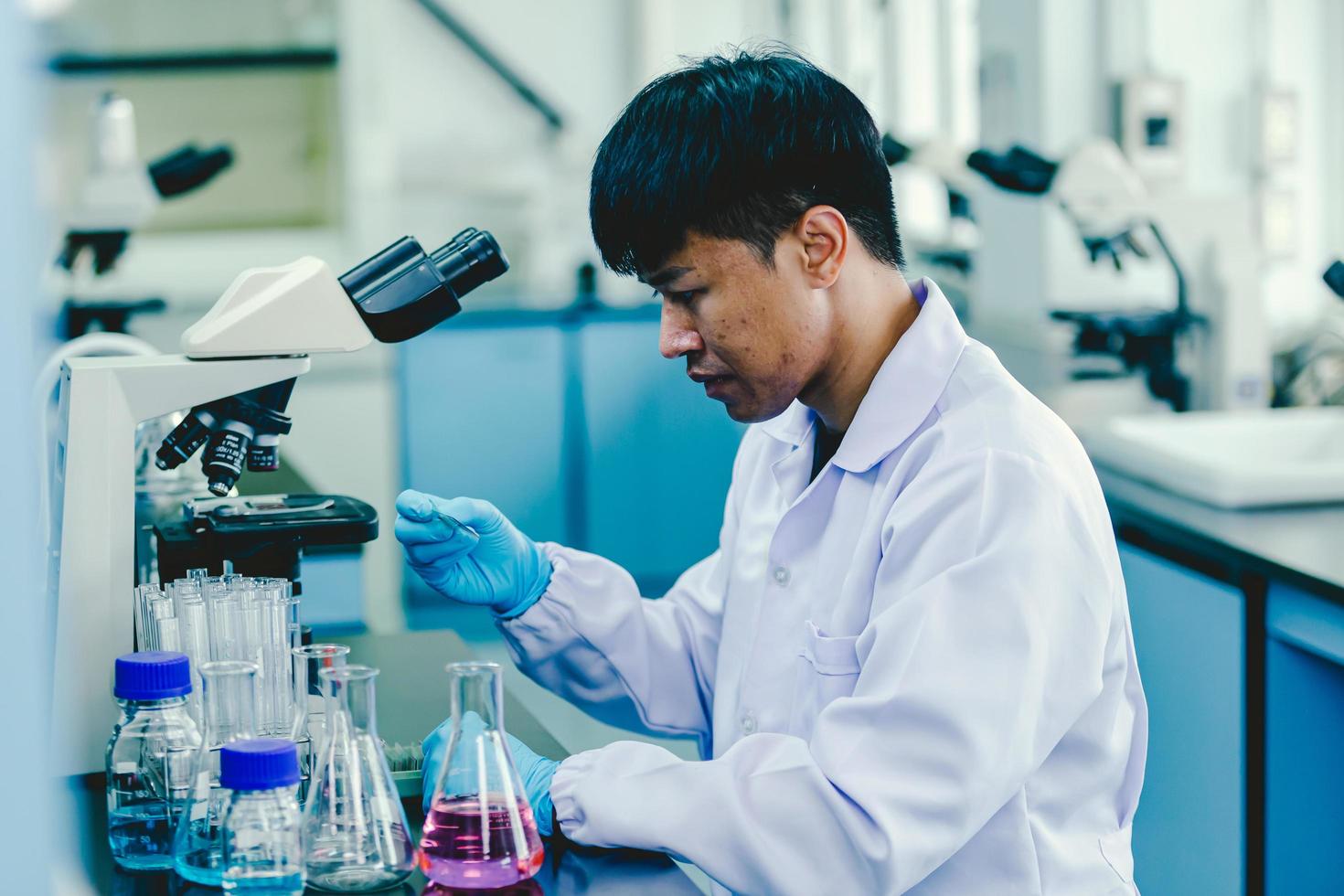 Aziatisch mannetje medisch of wetenschappelijk onderzoeker of dokter werken in de laboratorium.geavanceerd wetenschappelijk laboratorium voor geneesmiddel, biotechnologie, microbiologie ontwikkeling foto