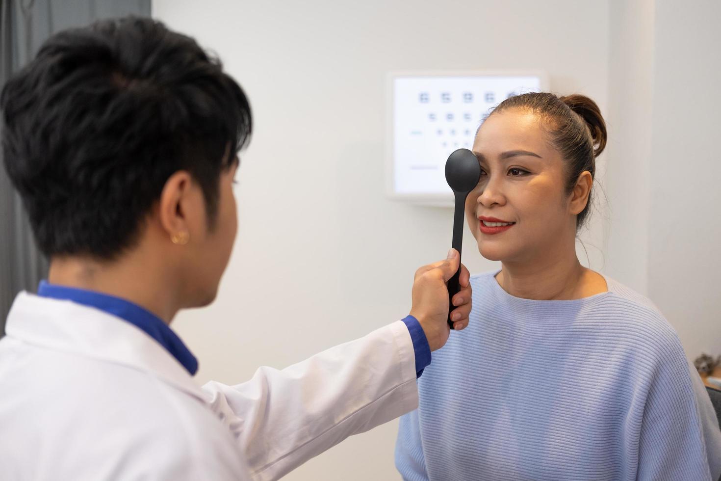 selectief focus Bij optometrist gezicht. terwijl dokter gebruik makend van zaklamp en subjectief breking naar onderzoeken oog zichtbaar systeem van ouderling geduldig Dames met professioneel machine voordat gemaakt bril. foto