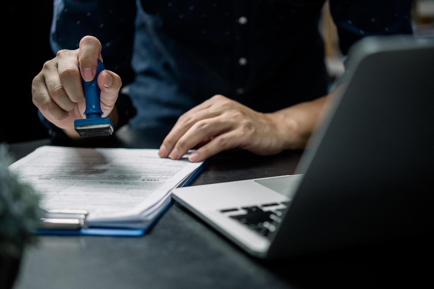 Mens stempelen goedkeuring van werk financiën bank of investering afzet documenten Aan bureau. foto