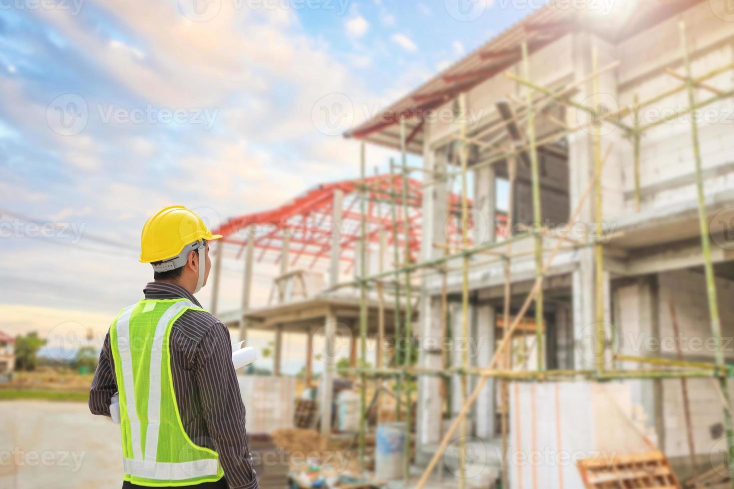 jong professioneel ingenieur in beschermend helm en blauwdrukken papier Bij de huis gebouw bouw plaats foto