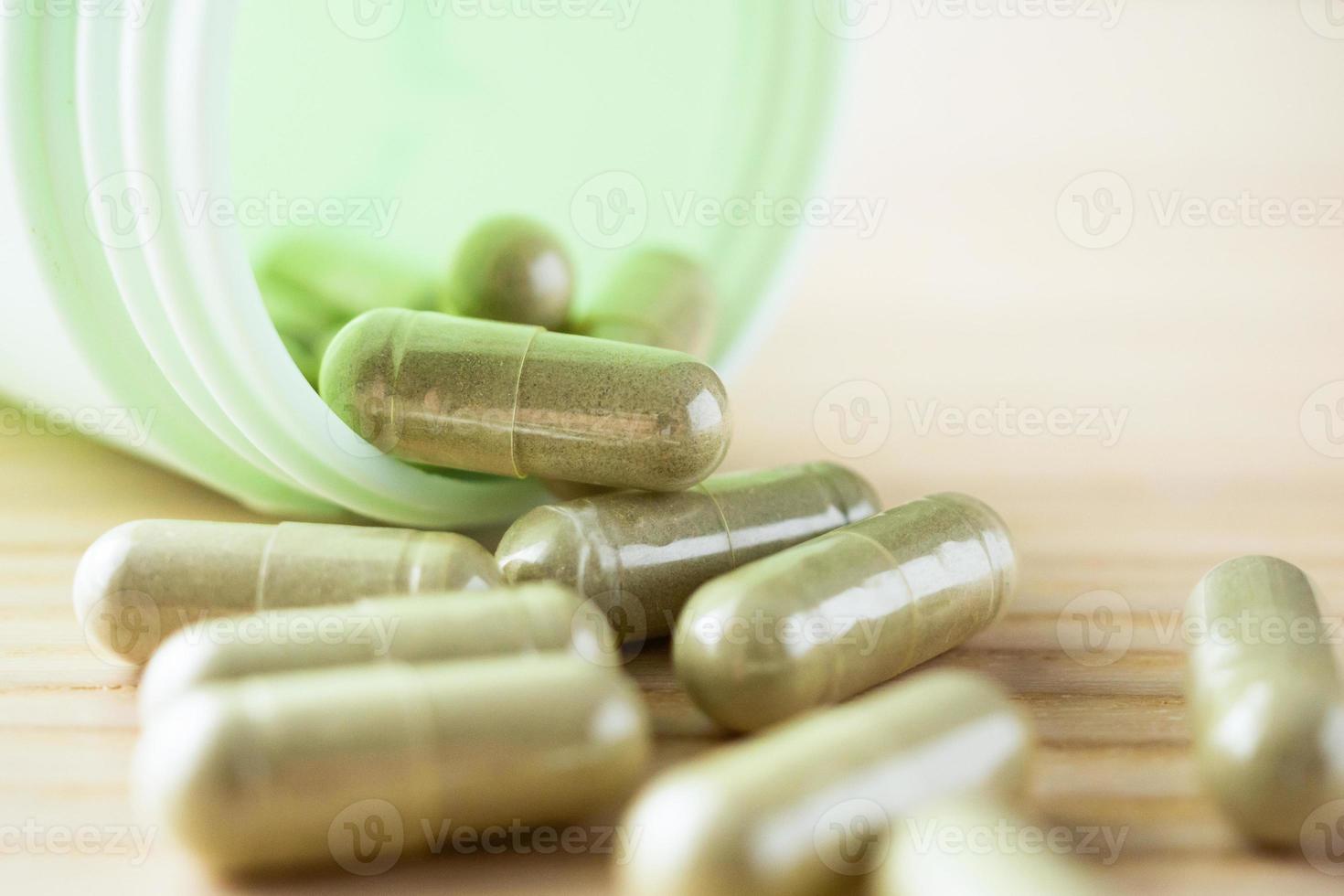 kruiden geneeskunde capsules met fles Aan hout tafel foto