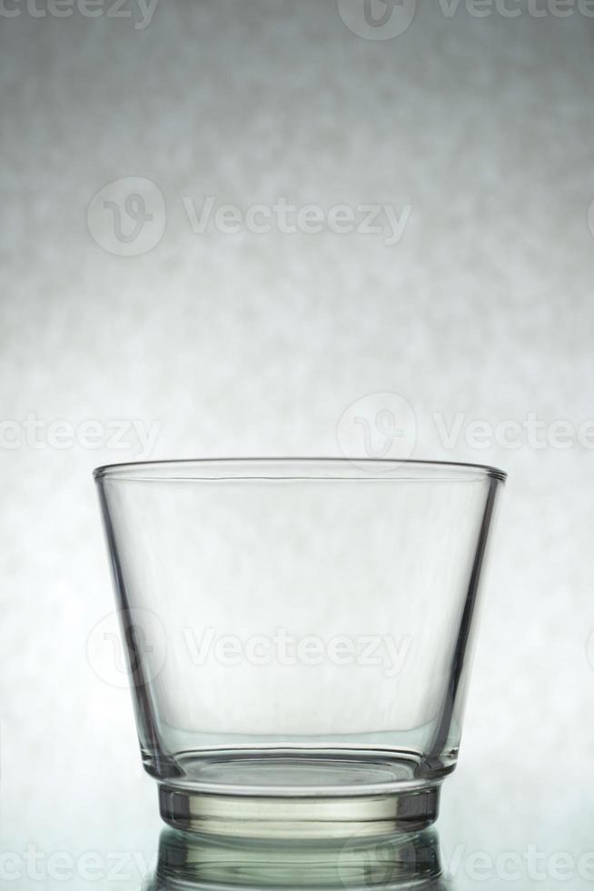 een verticaal schot van een leeg glas Aan een grijs achtergrond foto