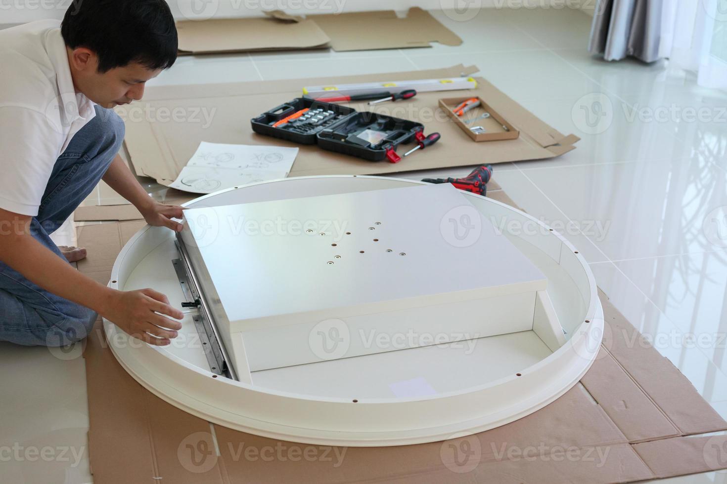 Aziatisch Mens in elkaar zetten wit tafel meubilair Bij huis foto