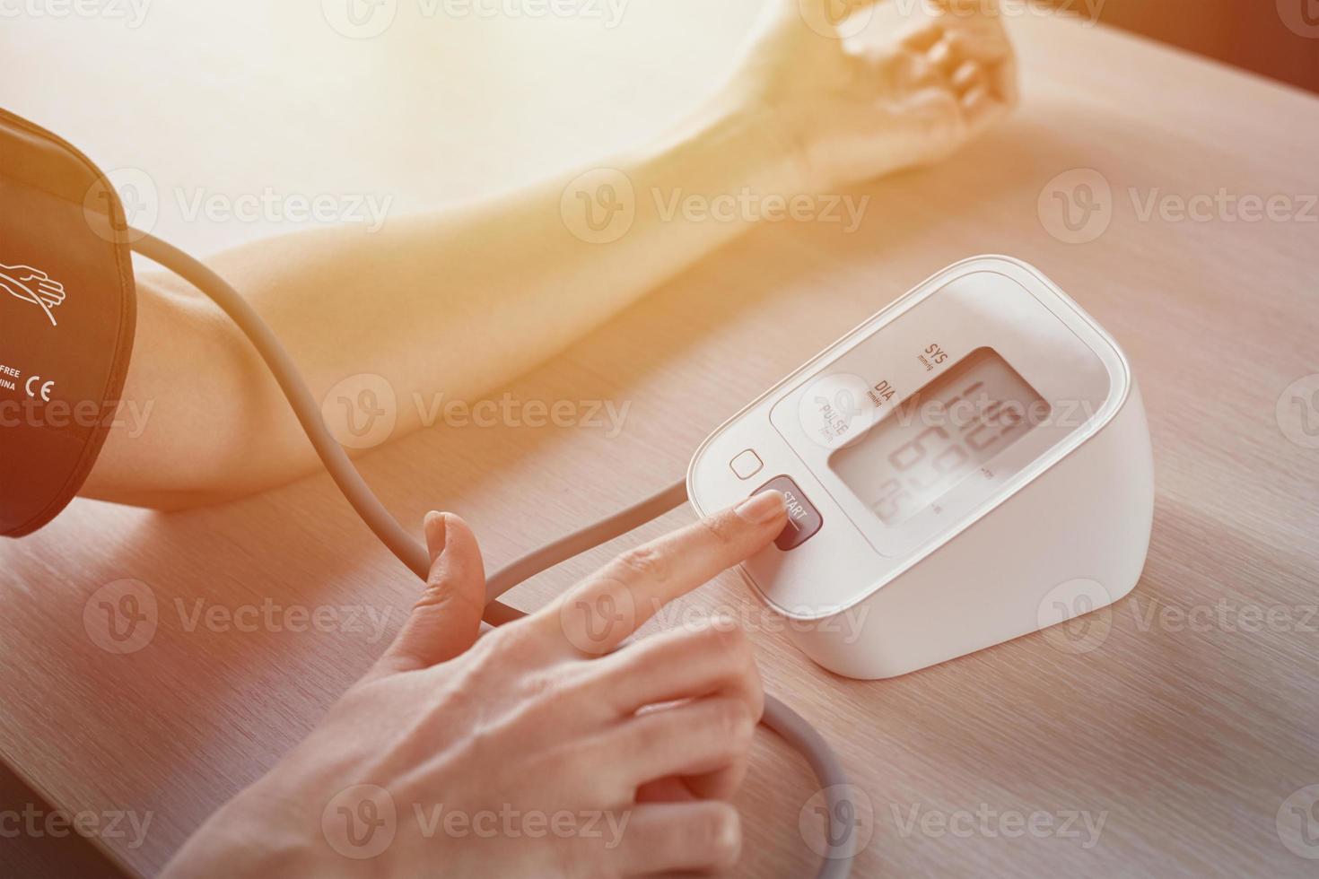 vrouw meten bloed druk met een elektrisch digitaal tonometer. gezondheidszorg en geneeskunde concept foto