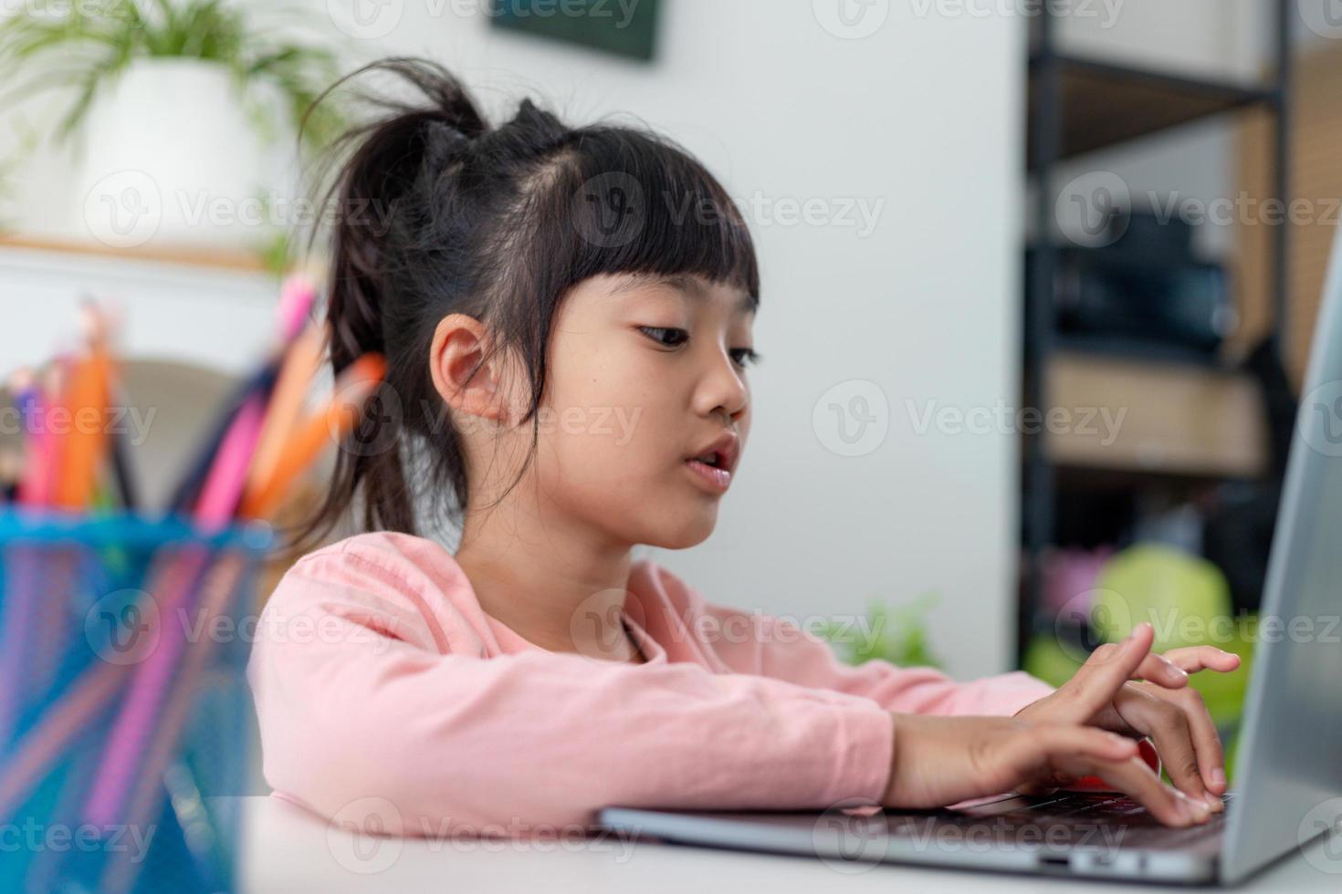 Aziatisch meisje met laptopcomputer voor online studie homeschooling tijdens thuisquarantaine. thuisonderwijs, online studeren, thuisquarantaine, online leren, coronavirus of onderwijstechnologieconcept foto