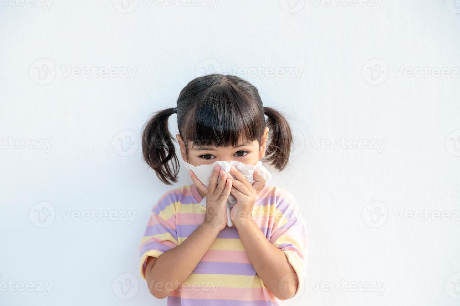 Aziatisch kind meisje ziek met niezen Aan de neus- en verkoudheid hoesten Aan zakdoek papier omdat zwak of virus en bacterie van stof weer en kleuterschool en peuter- foto