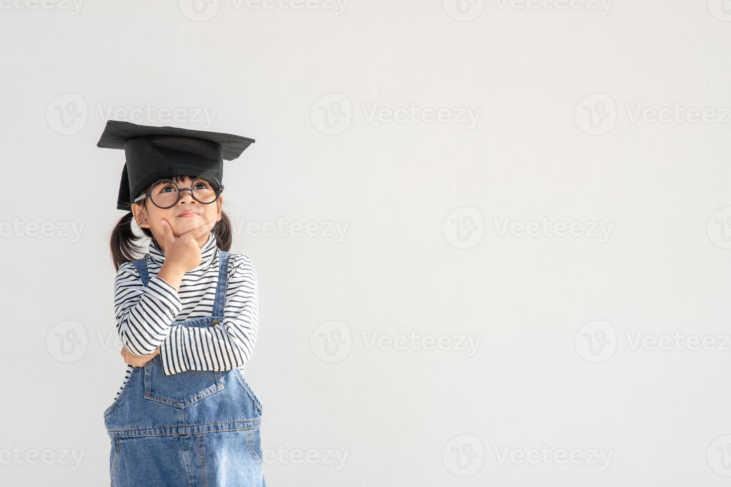 gelukkig aziatisch schoolkind afgestudeerd denken met afstudeerpet foto