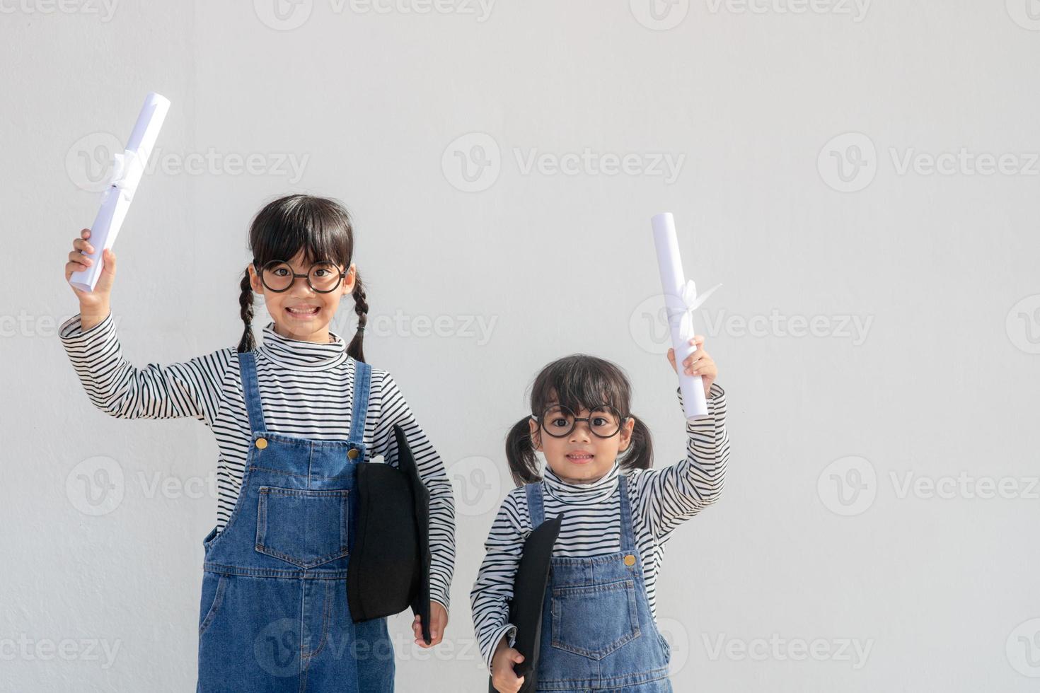 broers en zussen kinderen meisje diploma uitreiking met pet en diploma over- wit. foto