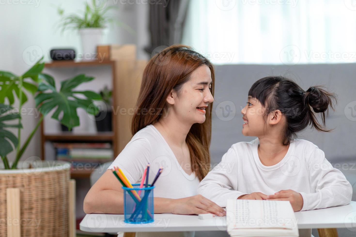 mooi Aziatisch vrouw helpen haar dochter met huiswerk Bij huis. foto