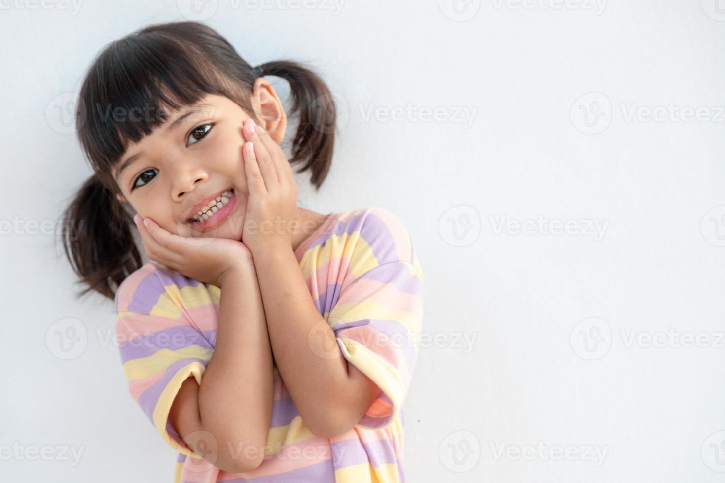 portret van verrast schattig weinig kleuter meisje kind staand geïsoleerd over- wit achtergrond. op zoek Bij de camera. handen in de buurt Open mond foto