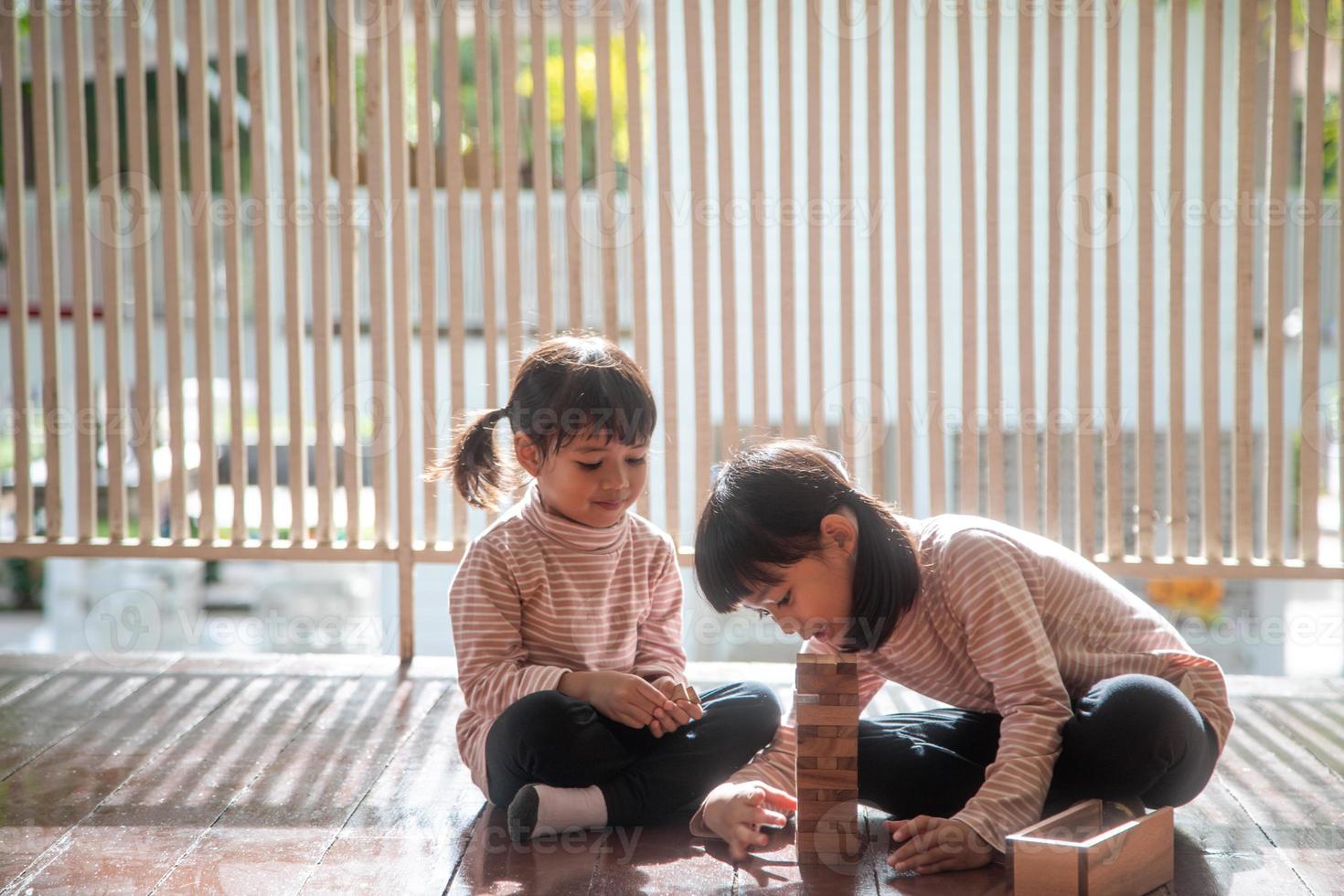 twee Aziatisch meisjes spelen houten stapels Bij huis foto
