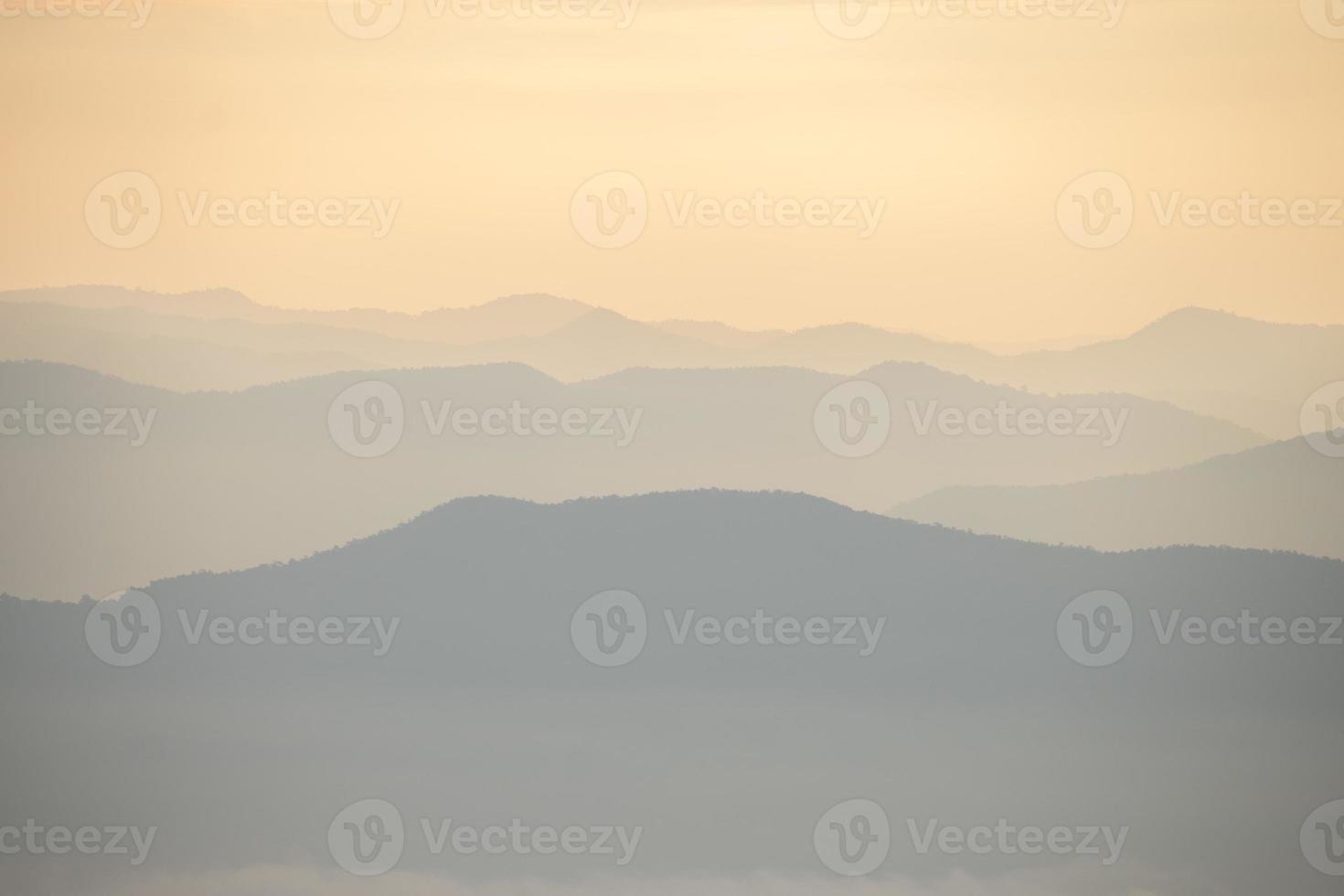 laag van bergen en de nevel gedurende zonsondergang foto