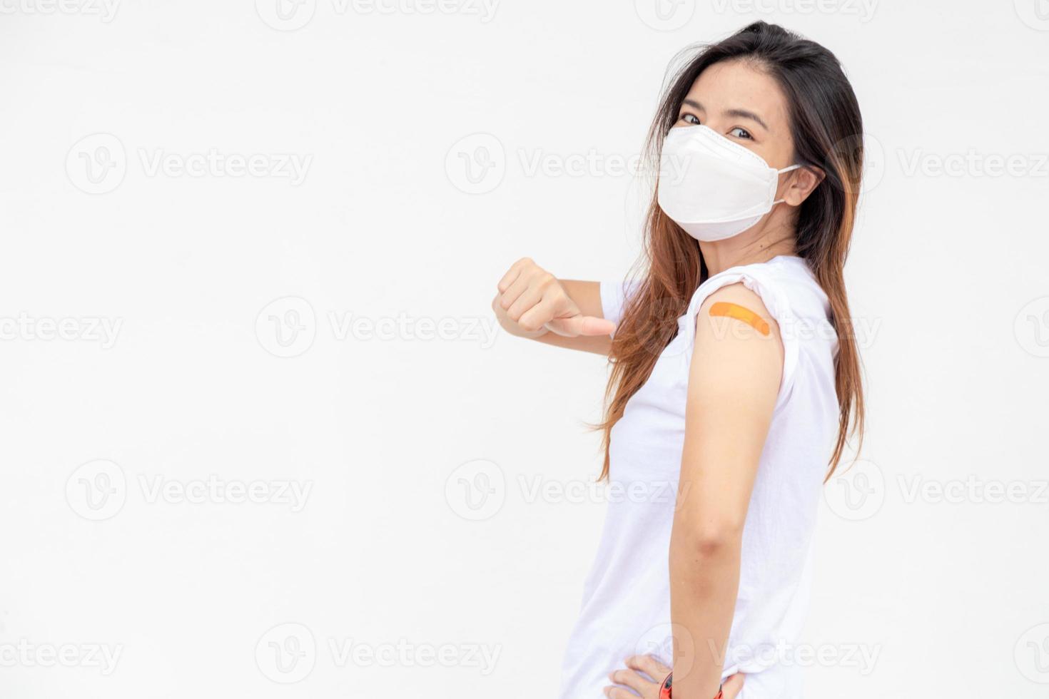 Aziatisch Dames tonen verband Aan arm. gelukkig Aziatisch vrouw voelt mooi zo na ontvangen vaccin Aan wit achtergrond. foto