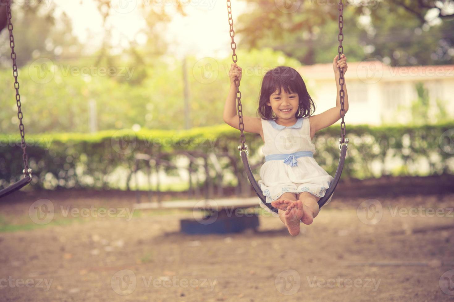 weinig meisje swinging Aan schommel Bij park foto