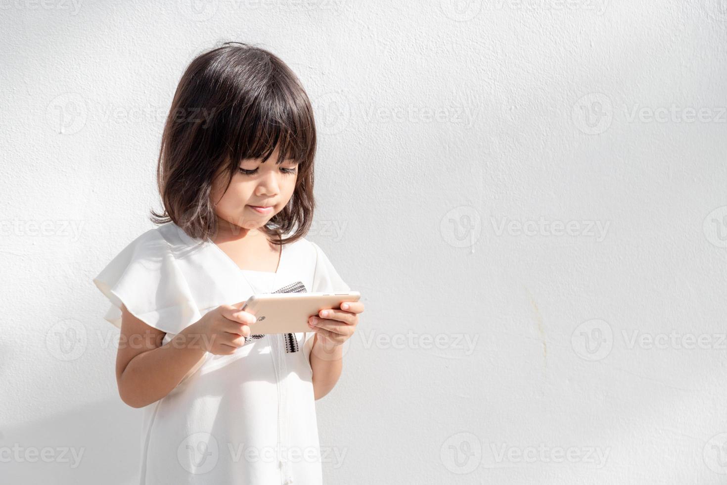 foto van een weinig meisje gebruik makend van een mobiel telefoon geïsoleerd over- wit achtergrond