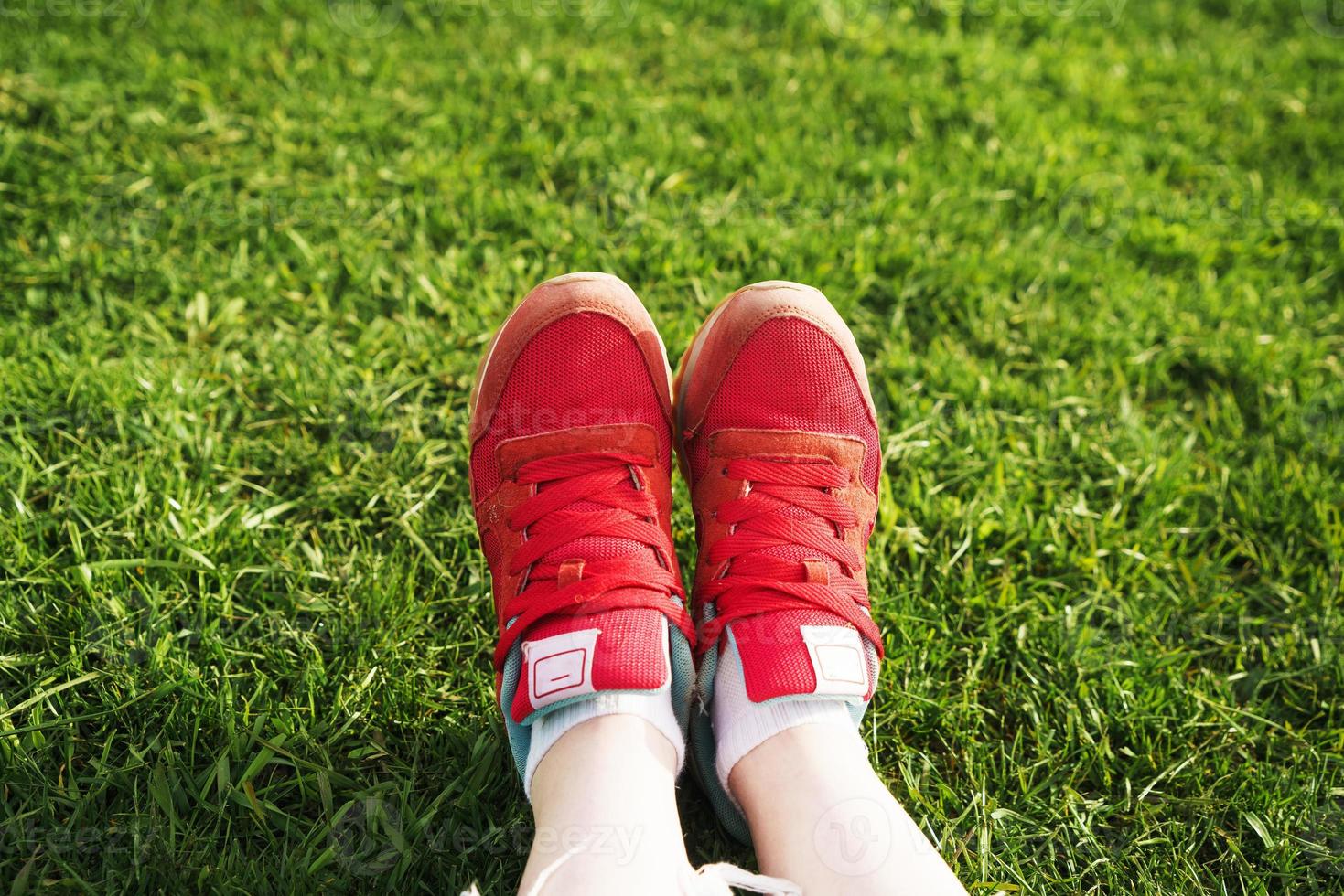 vrouwelijke benen in sneakers op een achtergrond van groen gras foto