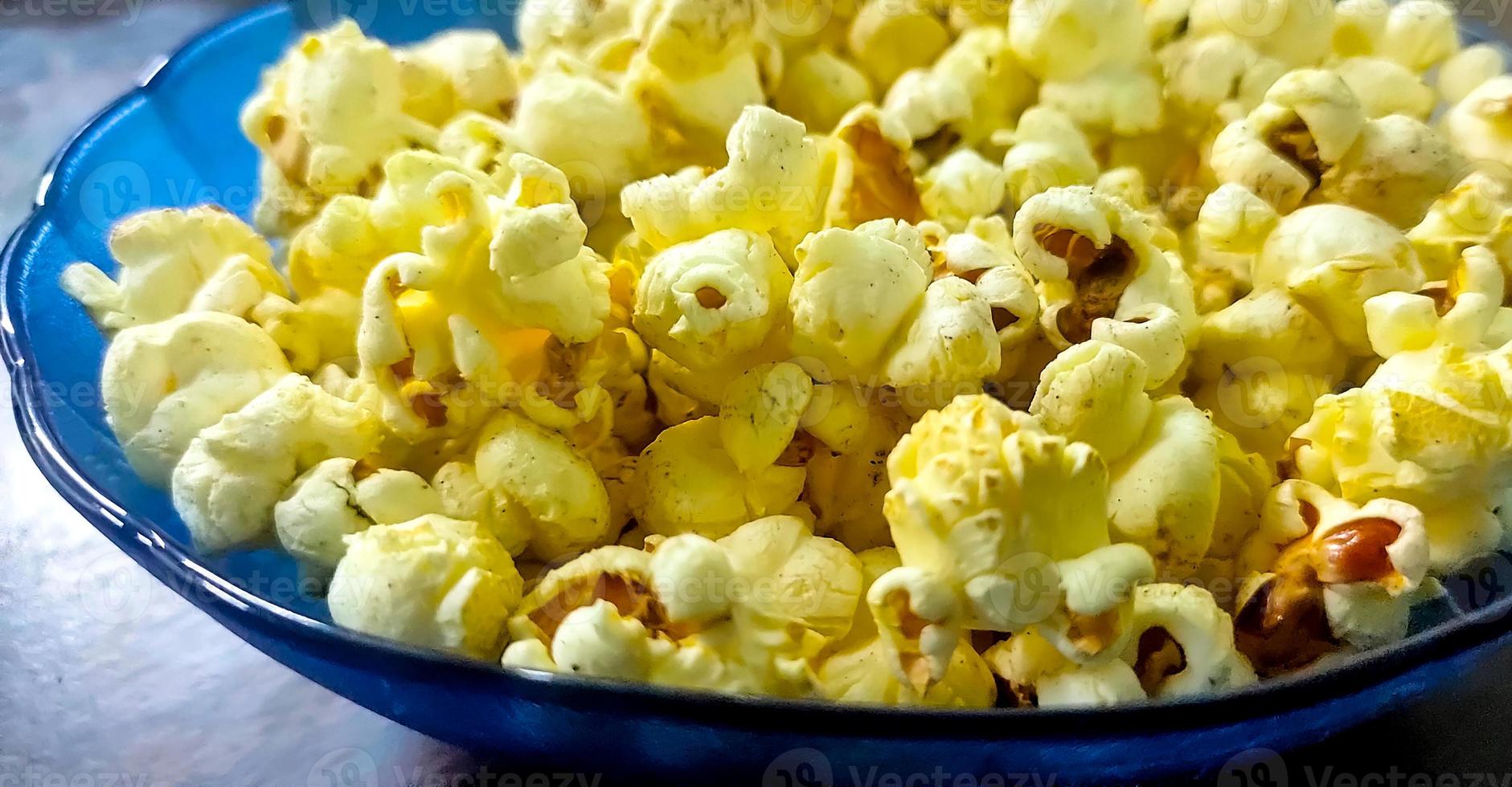 popcorn in een blauwe kom op houten tafel foto