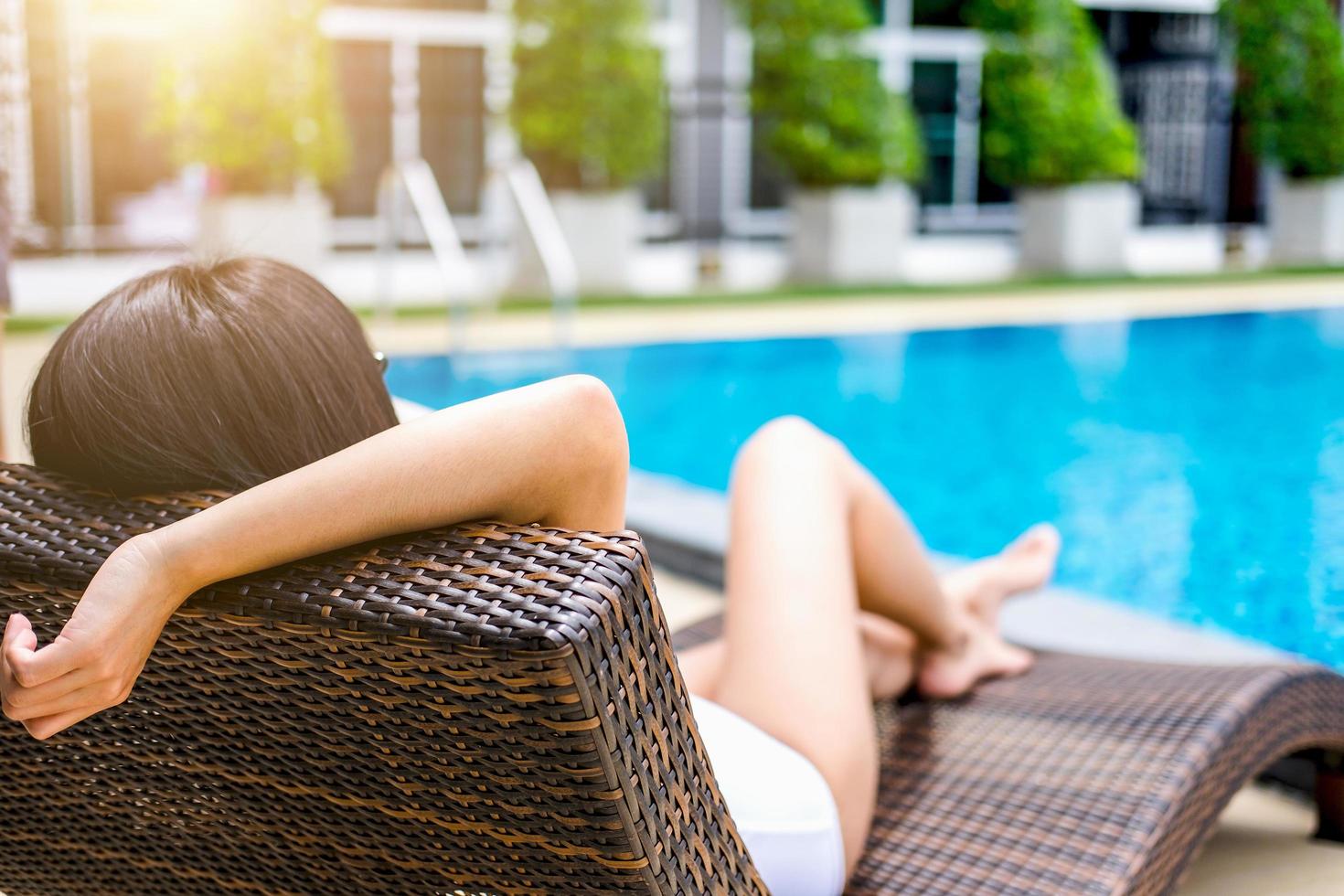gelukkig mooie vrouw ontspannen zonnebaden in de buurt van luxe zwembad foto