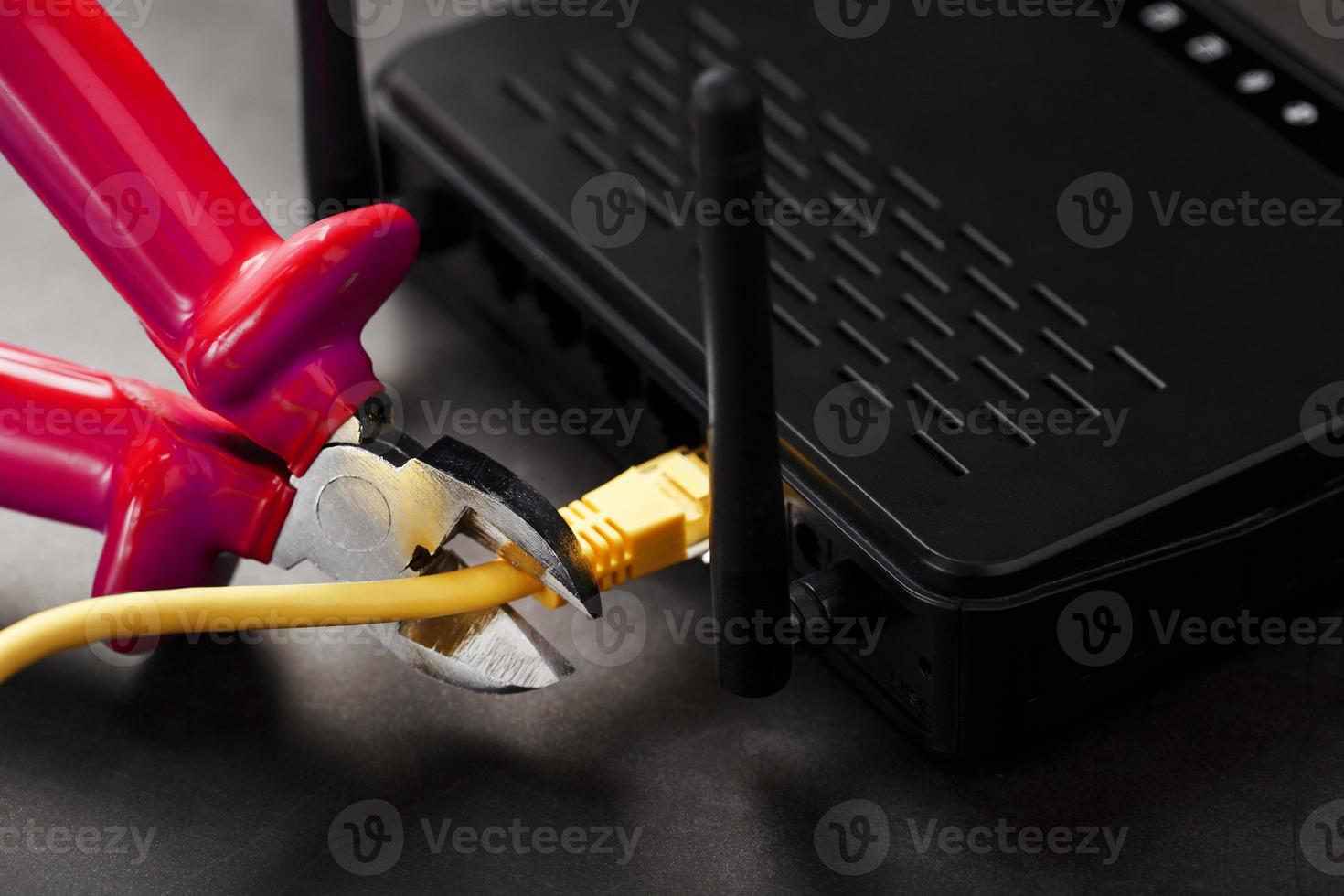 loskoppelen de internet verbinding, snijdend uit de geel ethernet kabel met draad snijders met een rood omgaan met Aan de Wifi router. foto