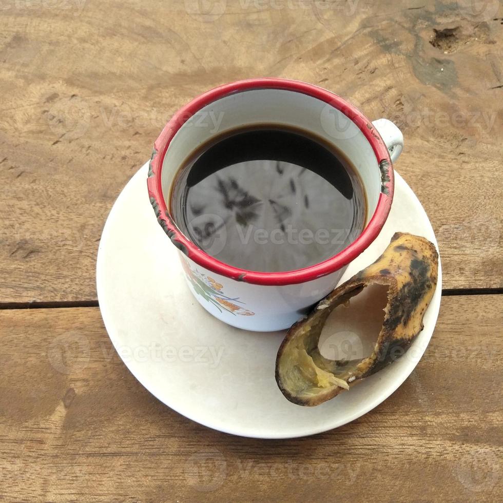 een kop van zwart koffie zittend Aan een tafel gemaakt van houten planken foto