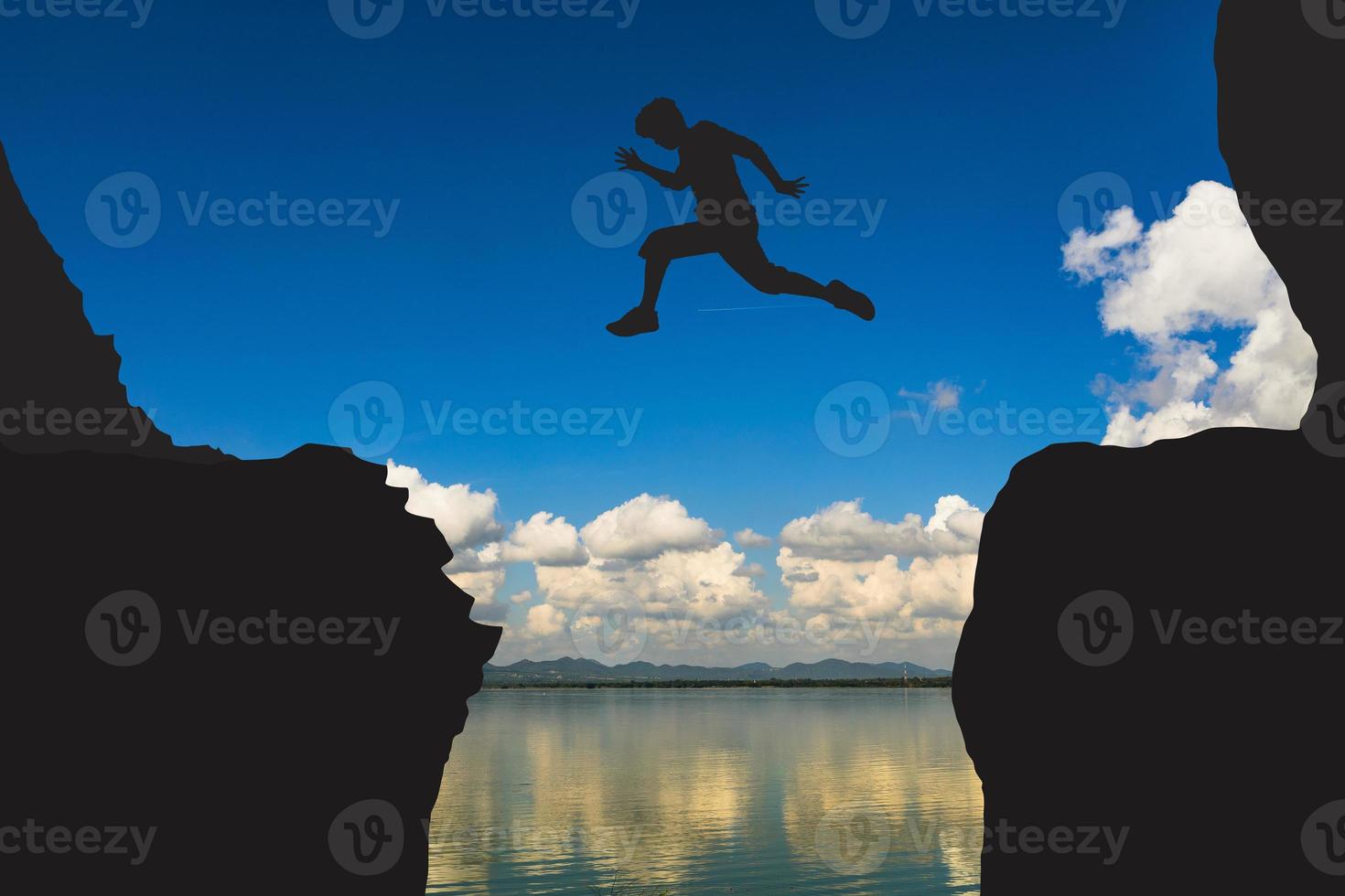 een silhouet van een Mens jumping over- een klif in zijn manier naar zege. foto