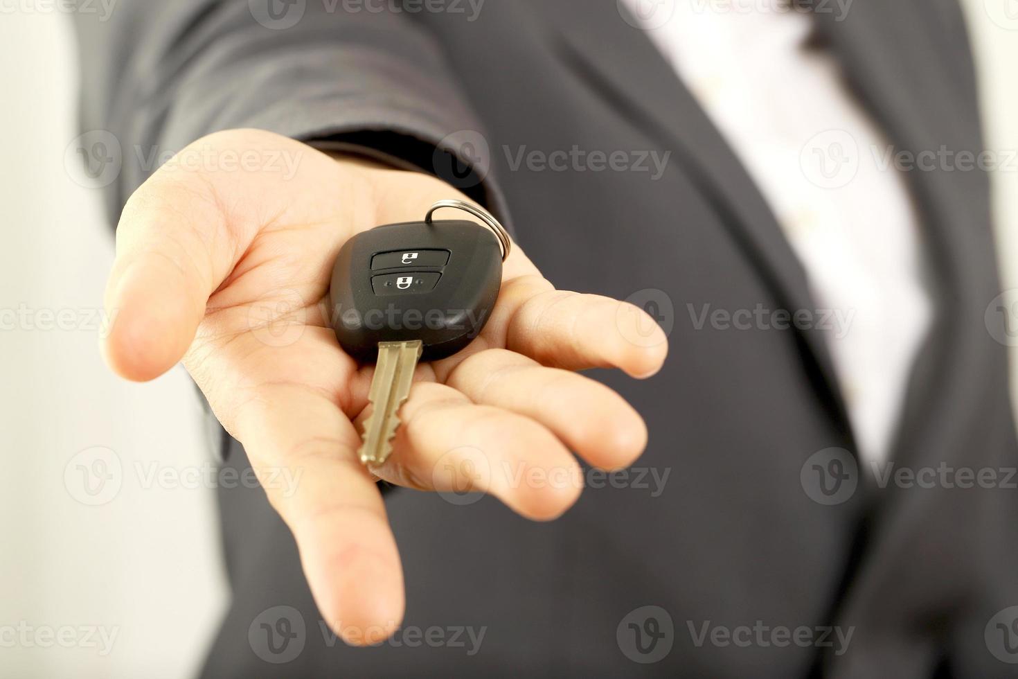 verkoper is draag- de auto sleutels geleverd naar de klant Bij de toonzaal met een laag interesseren bieden. speciaal Promotie foto